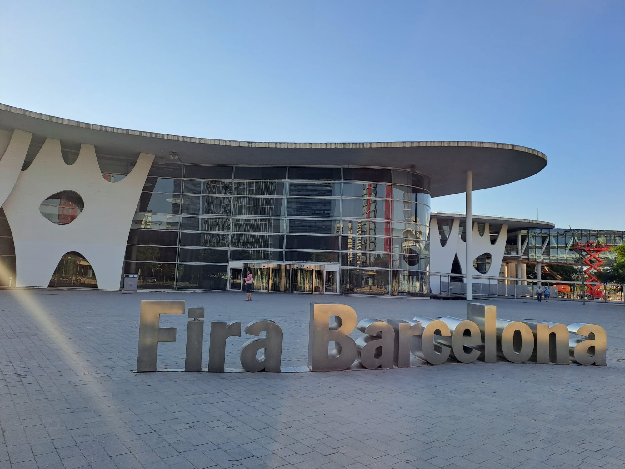 The name of the venue Fira Barcelona in big, 3D letters in the foreground and the building of the convention center in the background.
